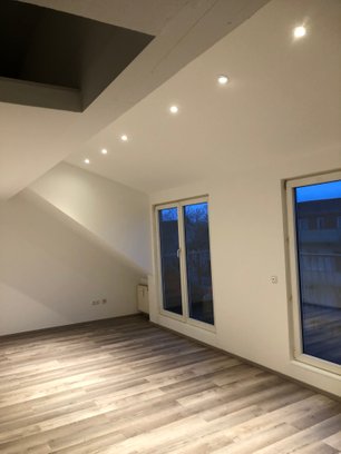 Wohnzimmer Renoviertes Wohnzimmer mit neuem dunklem Laminatboden und LED-Strahlern
