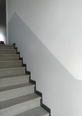 Treppenhaus mit weißen Wänden und grauen Stufen