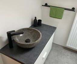 Aufsatzwaschbecken aus Stein in Grau mit schwarzer Armatur
